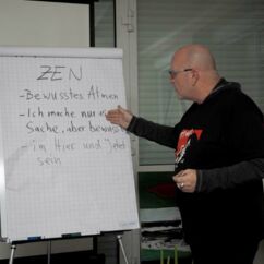 Bild zeigt Bluesharp-Spieler-Rick-Walter am Flipchart bei der Erklärung zu Atemübungen